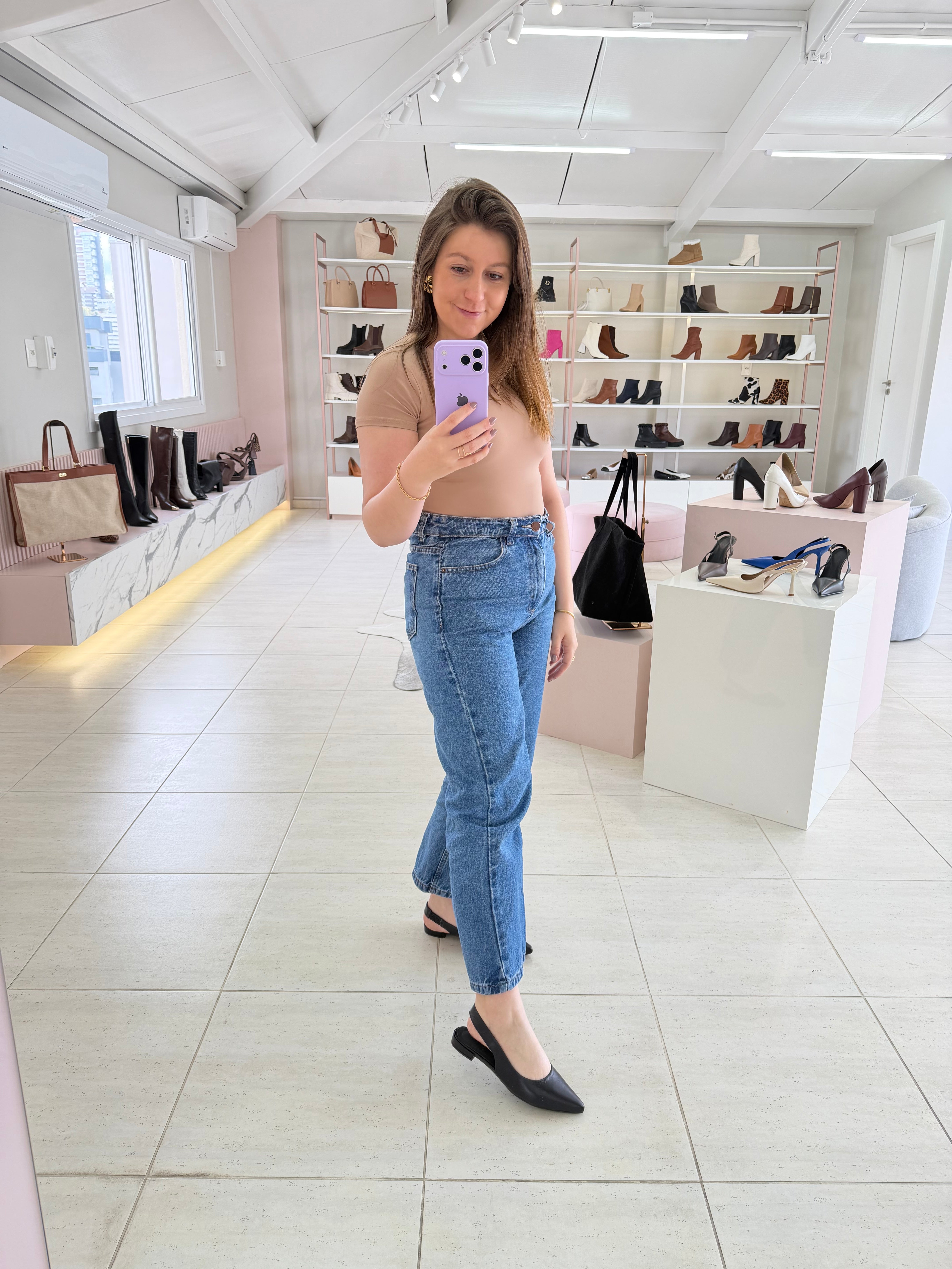 Mulher usando slingback Beyou Shoes preto de couro com bico fino em loja de calçados com prateleiras ao fundo