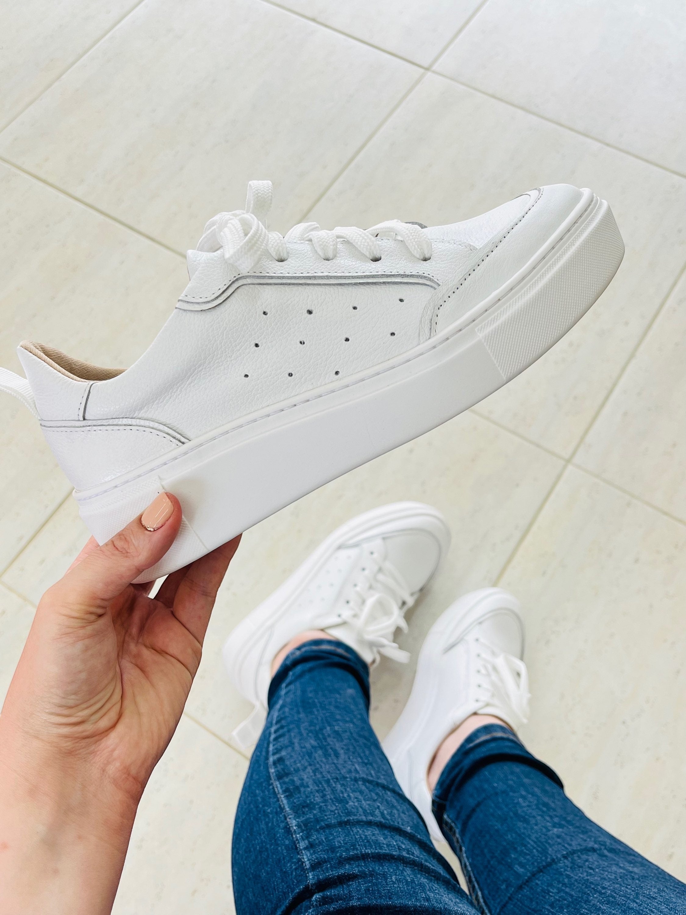 Tênis Beyou Shoes Chicago branco em couro com solado plataforma, segurado por uma mão sobre fundo claro.