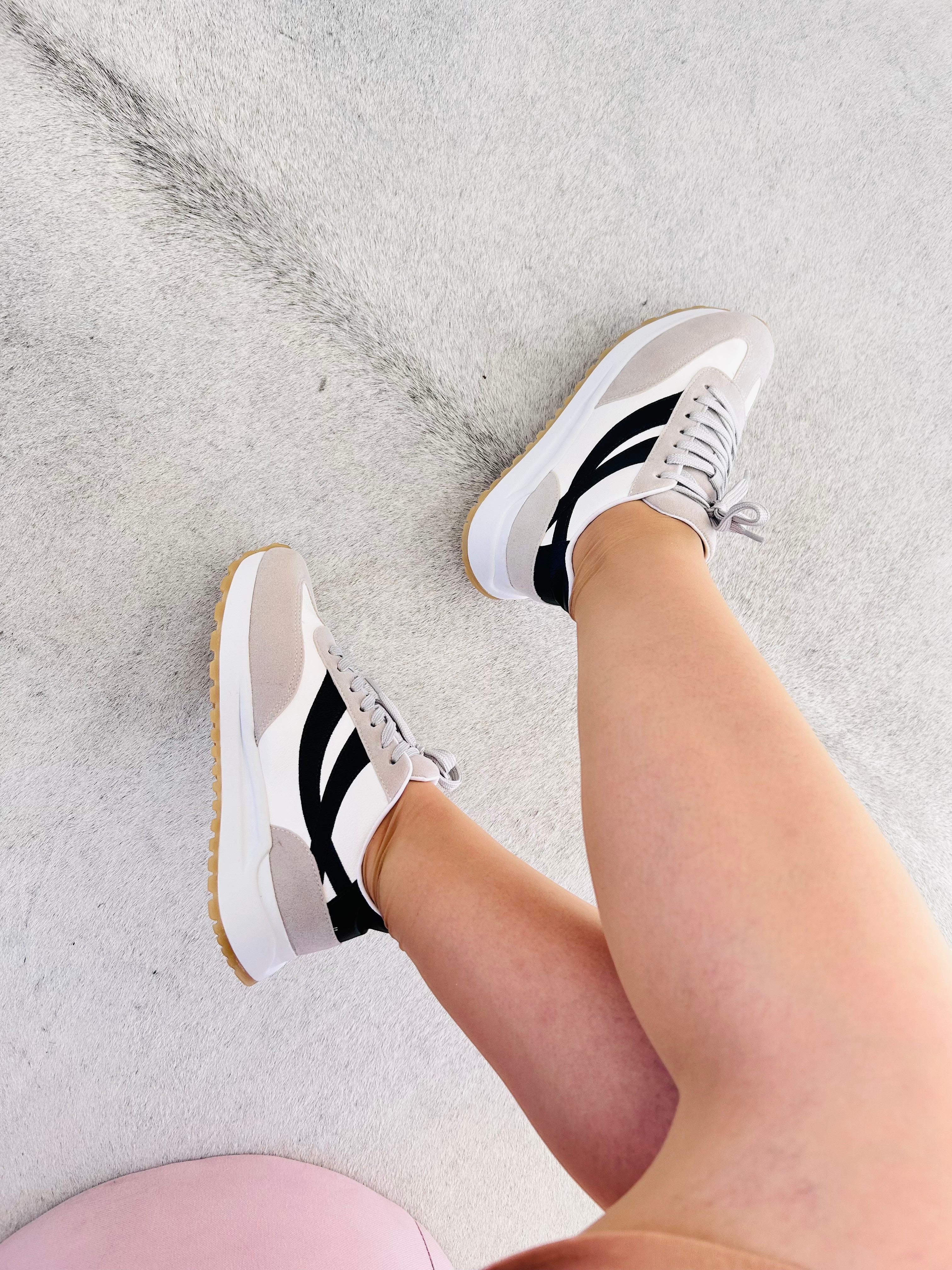 Tênis Beyou Shoes Oslo off white com detalhes em camurça sintética e solado esportivo, calçado no pé de uma modelo.